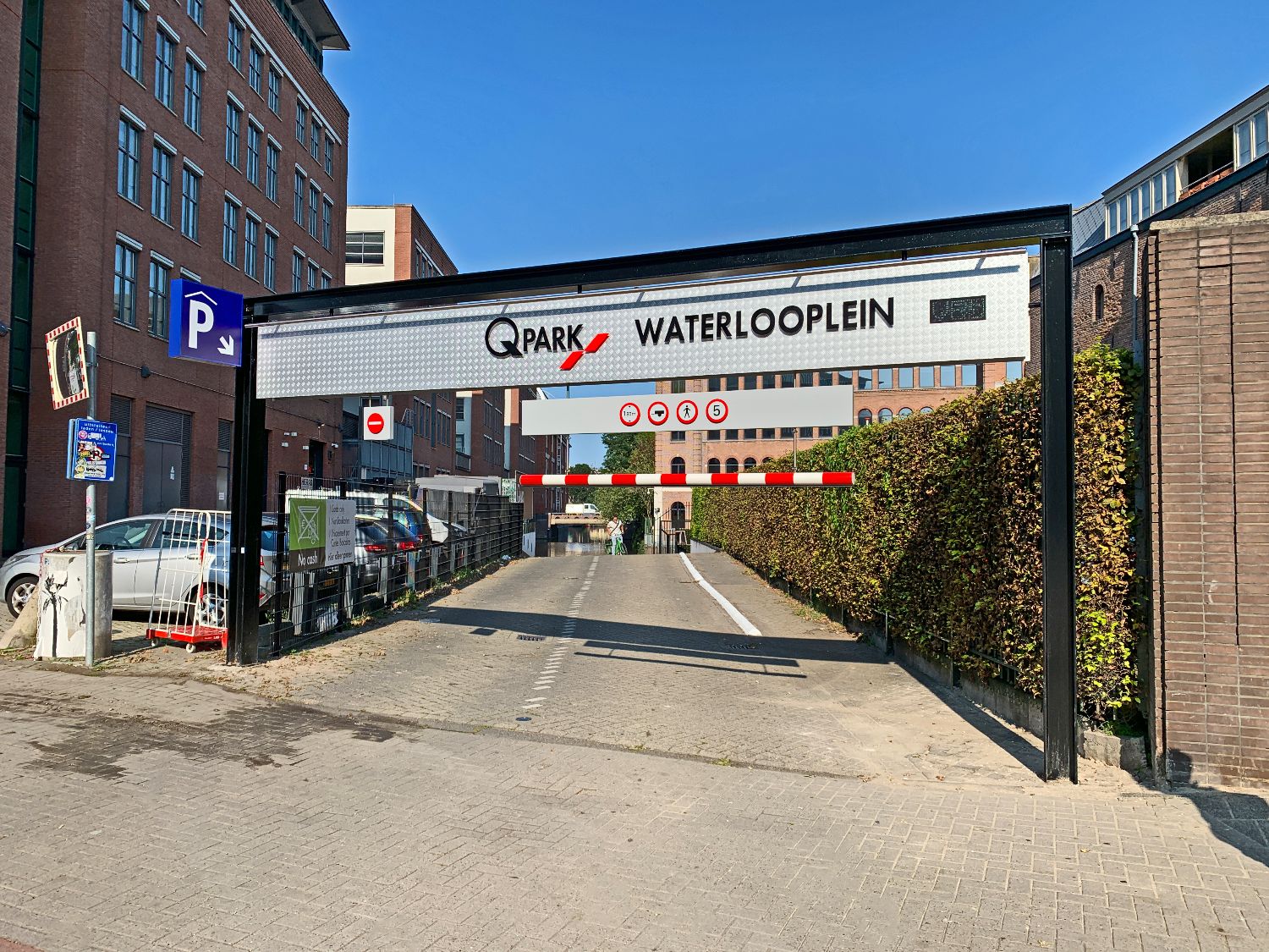 Entreeportaal met freesletters op traanplaat, hoogtebalk en uitsteeklichtbak bij inrit van parkeergarage Q-Park Waterlooplein in Gemeente Amsterdam.
